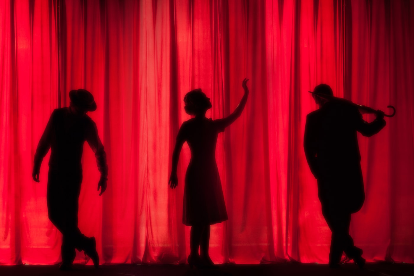 Silhouetted performers on a red-lit stage — drama, voice and public speaking